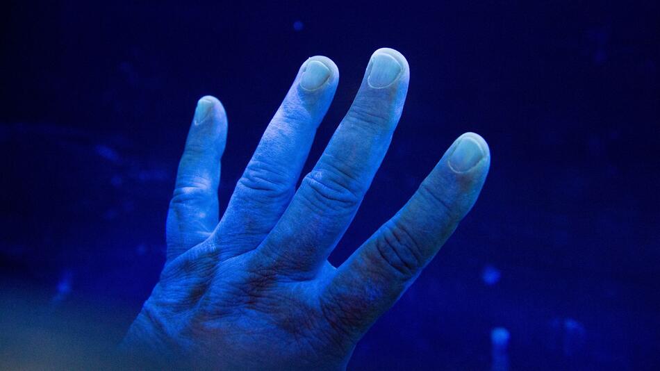 Desinfizierte Hand wird unter eine UV-Lampe gehalten