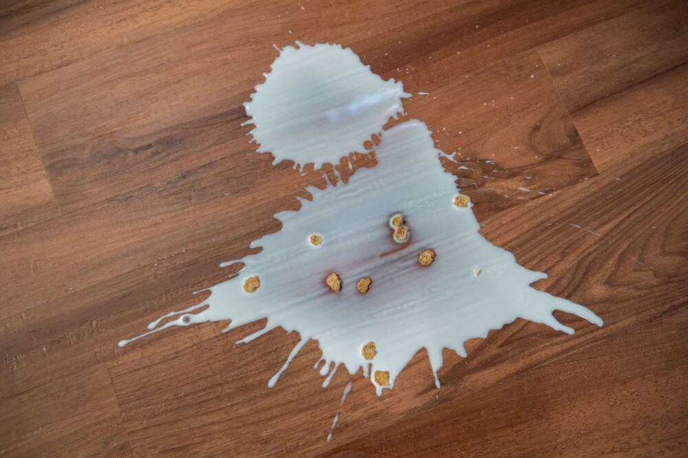 Ausgeschüttete Milch mit Cornflakes auf einem Fußboden