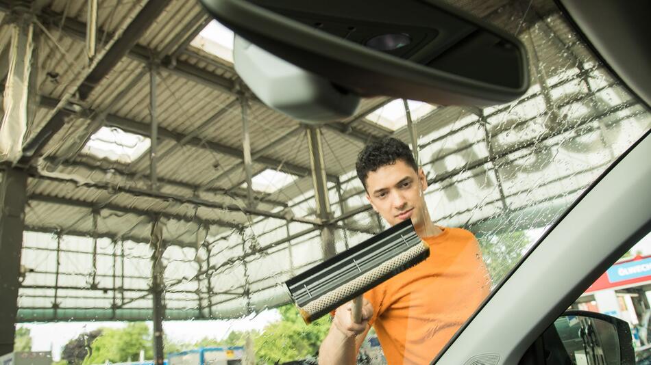 Ein Mann reinigt die Windschutzscheibe seines Autos