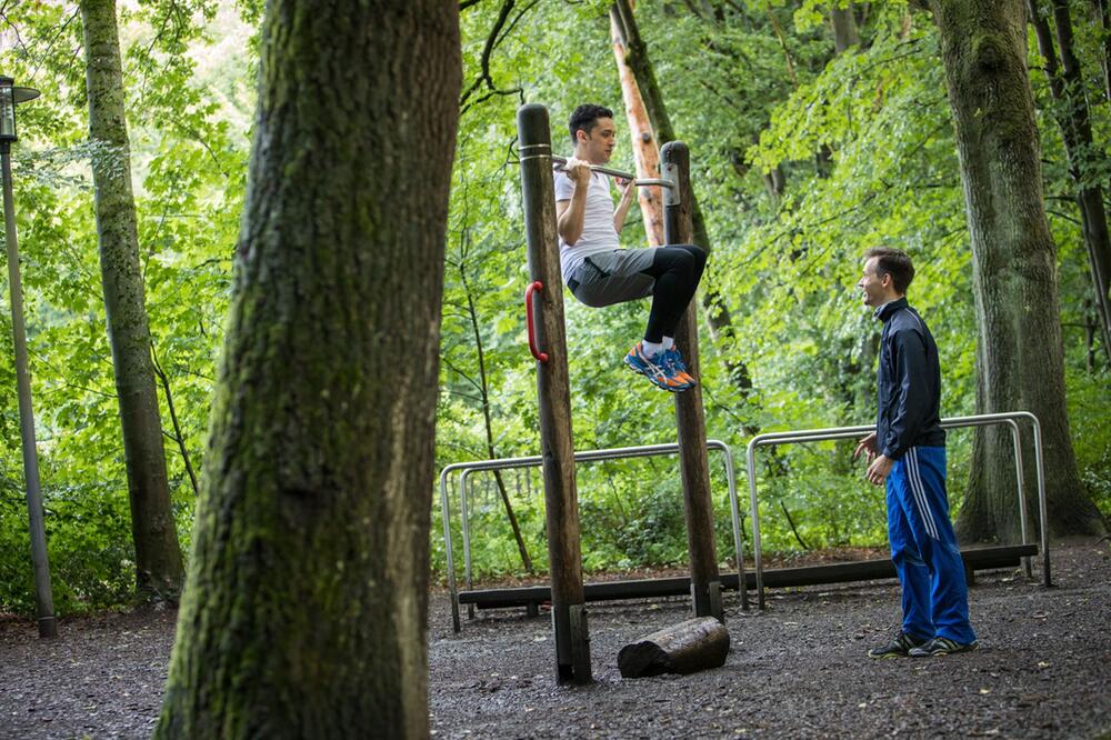 Ein Mann trainiert Klimmzüge im Park