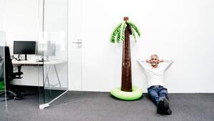 Mann sitzt im Büro neben einer aufblasbaren Palme