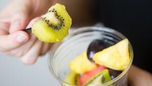 Mann isst geschnittenes Obst aus einem Plastikbecher