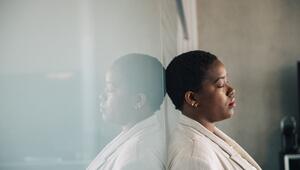 Eine junge Frau lehnt nachdenklich an einer Glaswand