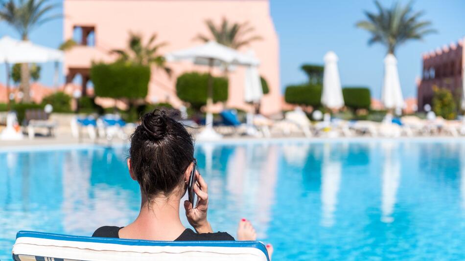 Frau telefoniert am Hotelpool
