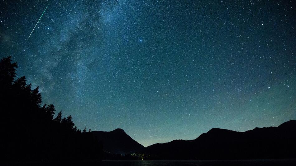 Eine Sternschnuppe leuchtet am Himmel über dem Walchense (Bayern)