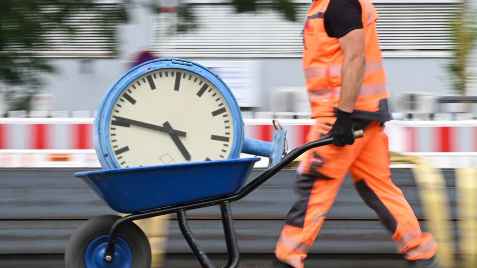 Ein Arbeiter transportiert eine Bahnhofsuhr auf einer Schubkarre