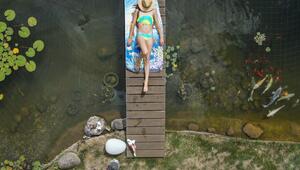 Mädchen sonnt sich auf einer Brücke über einem Gartenteich