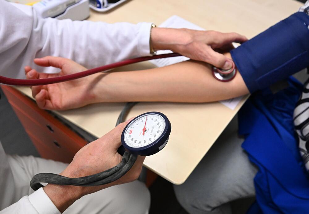 Ein Arzt misst bei einer Patientin den Blutdruck