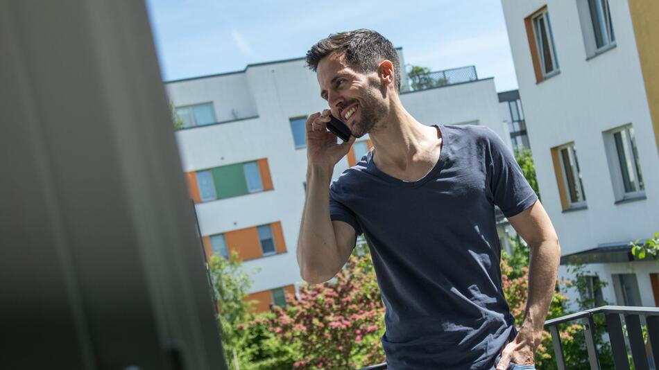 Mann telefoniert auf einem Balkon