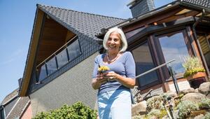 Eine Frau steht im Garten vor ihrem Haus