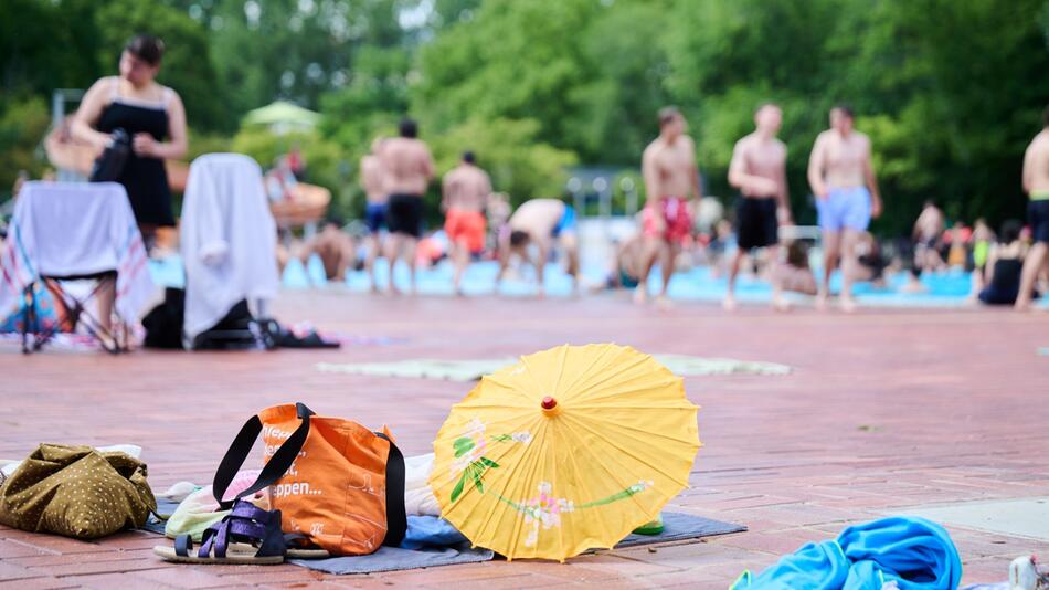 Handtücher und Rücksäcke liegen am Beckenrand eines Freibads