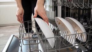 Eine Person sortiert Teller in eine Geschirrspülmaschine
