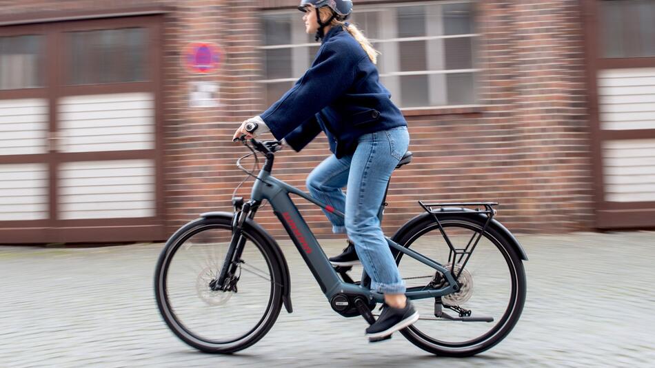 Eine junge Frau fährt auf einem E-Trekkingbike