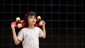 Selbstbewußter Junge trägt ein Skateboard auf seinen Schultern