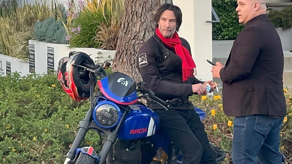 Keanu Reeves lehnt lässig auf einer Maschine seiner eigenen Firma Arch Motorcycle Company.