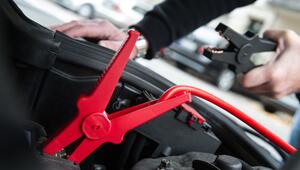 Ein Mann hält die Klemme eines Starthilfekabels