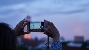Frau fotografiert mit dem Smartphone den Abendhimmel über Berlin