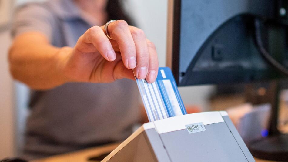 Eine Frau liest eine Versichertenkarte aus