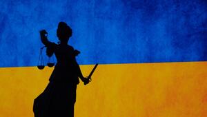 Eine Justitia-Figur vor der ukrainischen Flagge