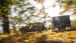 Ein Auto mit Anhänger fährt die Straße entlang