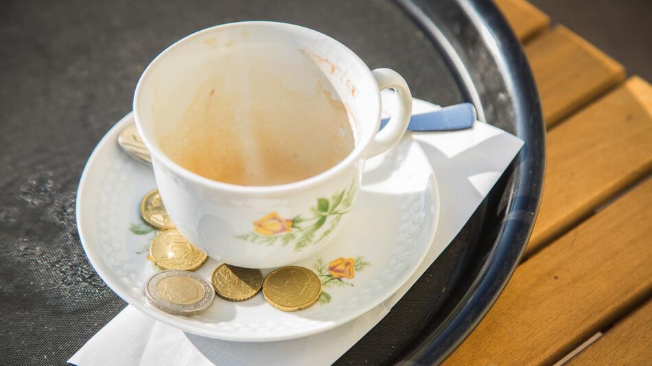 Trinkgeld liegt neben einem Cappuccino auf einem Tablett