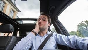 Ein Mann am Steuer fasst sich ins Gesicht