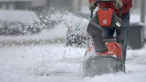 Mann räumt mit Hilfe einer Schneefräse den Gehweg