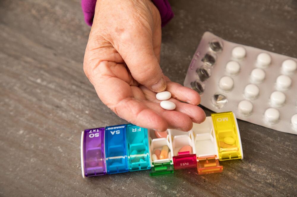 Frau nimmt Tabletten aus einer Pillendose