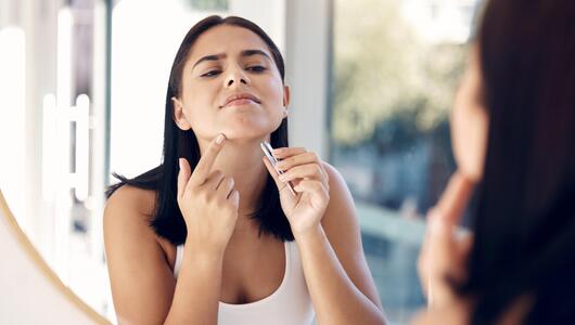 Frau rupft ein Haar am Kinn aus