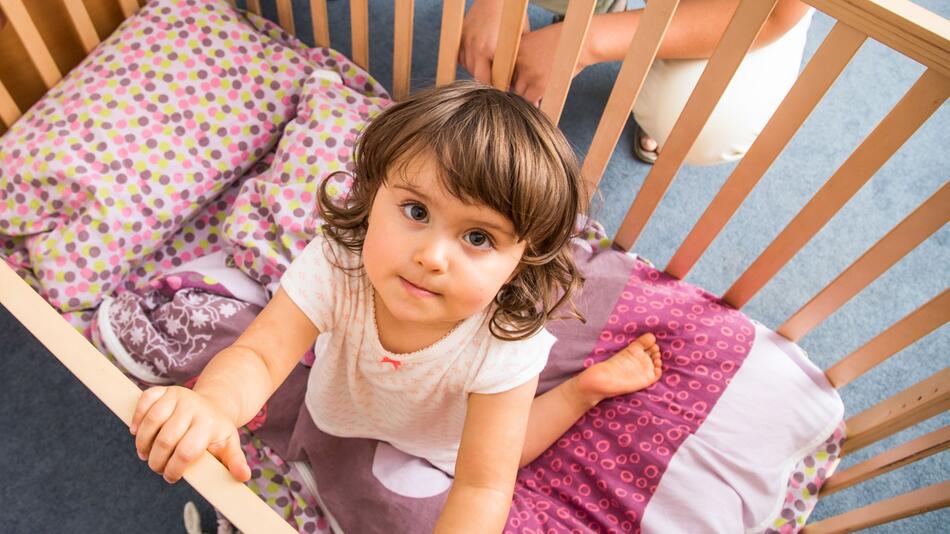 Mädchen schaut aus ihrem Kinderbett