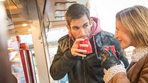 Ein Mann und eine Frau trinken Heißgetränk auf Weihnachtsmarkt