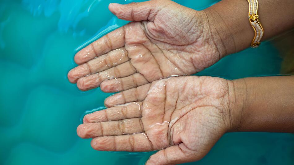 Schrumpelige Hände im Wasser