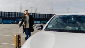 Geschäftsmann am Flughafen vor Mietwagen.