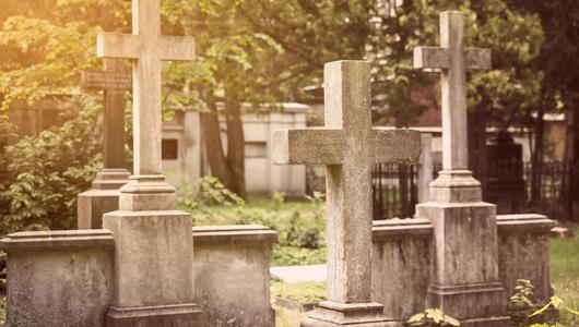 Blick auf mehrere steinerne Kreuze auf einem Friedhof