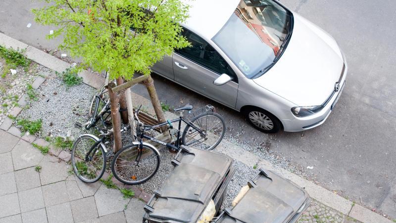 Parkendes Auto neben Mülltonnen