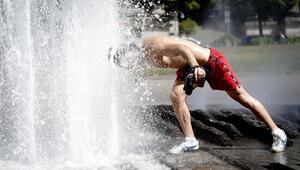 Ein Passant erfrischt sich bei großer Hitze am Brunnen