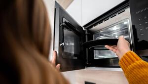Eine Frau gibt einen schwarzen Teller in eine Mikrowelle.