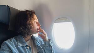 Eine Frau sitzt im Flugzeug am Fenster. Blende ist offen.