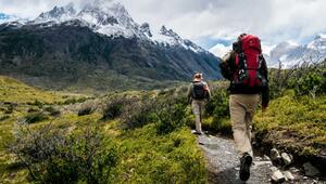 Zwei Wanderer mit Rucksäcken auf einem schmalen Pfad in einer bergigen Landschaft, im ...