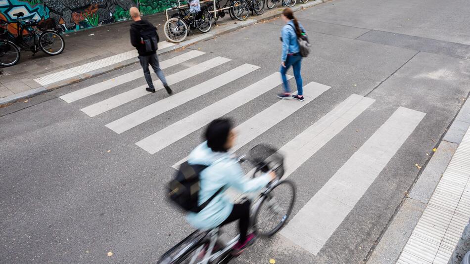 Radfahrer und Fußgänger überqueren einen Zebrastreifen