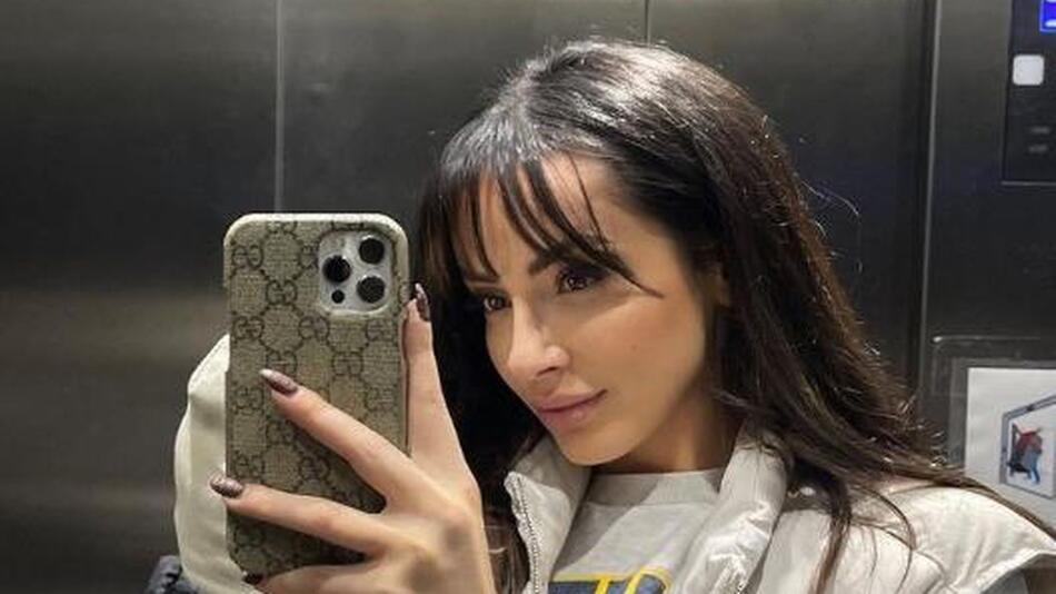 Jennifer Saro schaut in einem Aufzug auf ihr Handy