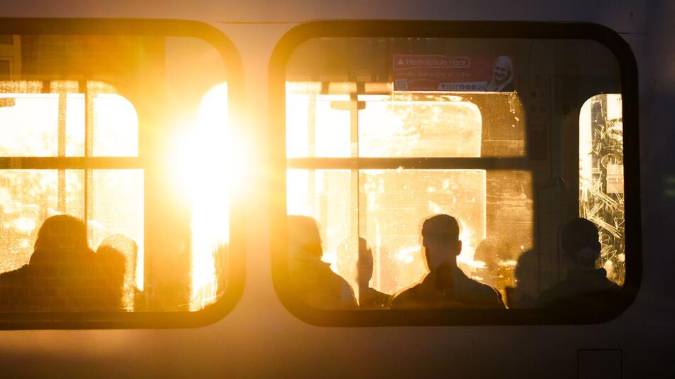 Fahrgäste sitzen bei Sonnenaufgang in einer Stadtbahn