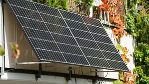 Zwei Solarpaneele sind an ein Balkongeländer montiert, umgeben von grünen und herbstlich ...