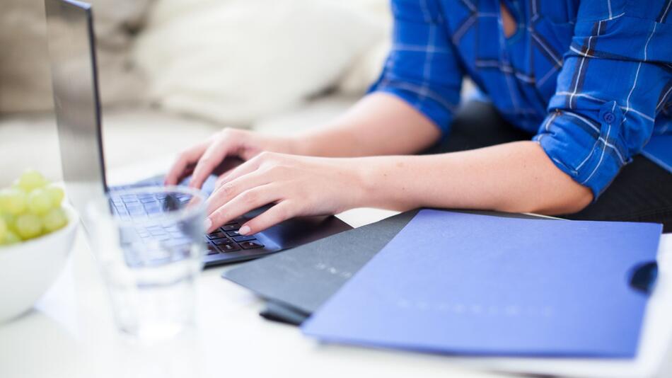 Frau schreibt Bewerbungen an einem Laptop