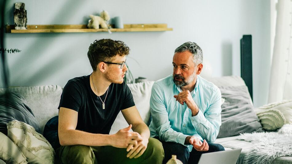 Vater und Sohn unterhalten sich im Wohnzimmer