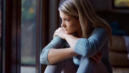 Junge Frau nachdenklich am Fenster