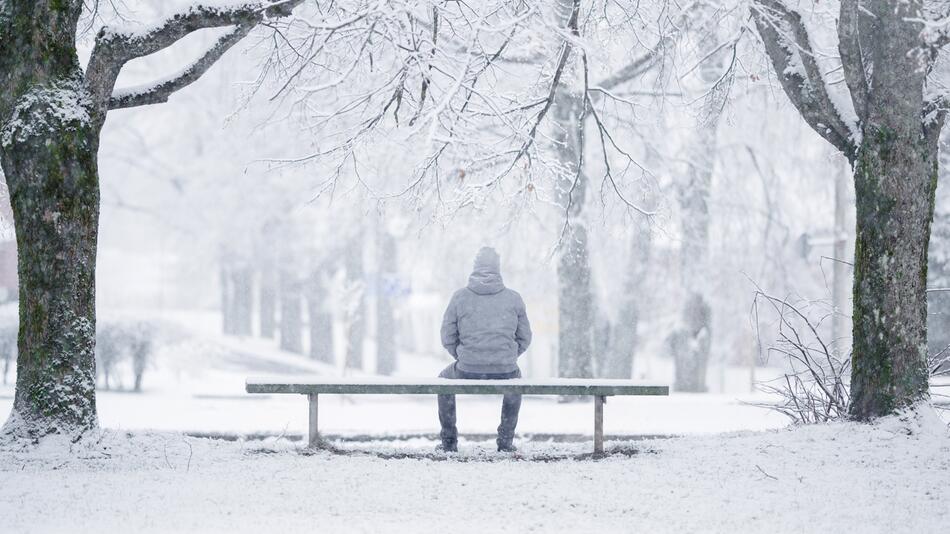 Mann sitzt im Schnee