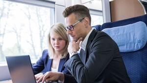 Zwei Personen arbeiten gemeinsam an einem Laptop im Zug