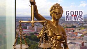Goldene Justitia-Statue mit Waage vor unscharfem Stadtpanorama, daneben Schriftzug "Good News" ...
