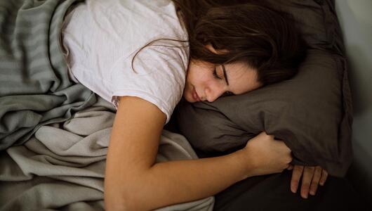 Junge Frau liegt im Bett und schläft